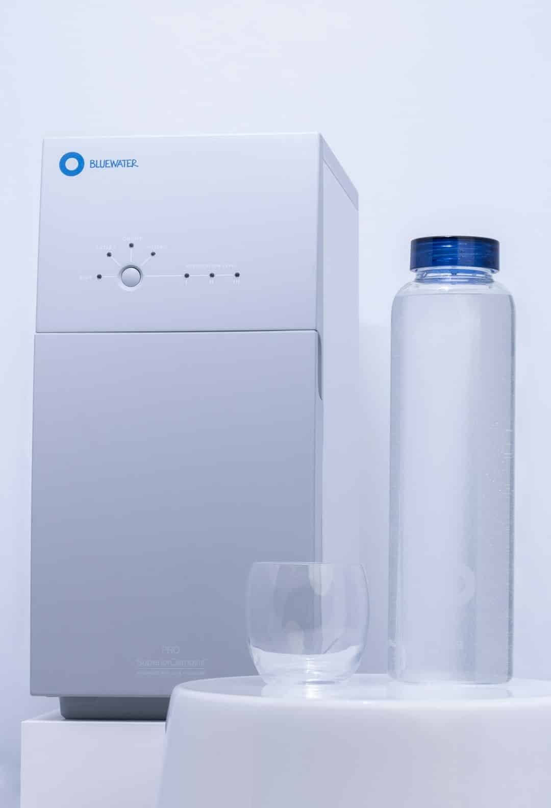 Modern water purification system with filled bottle and glass.